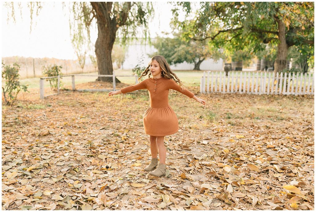 girl spinning in fall leaves