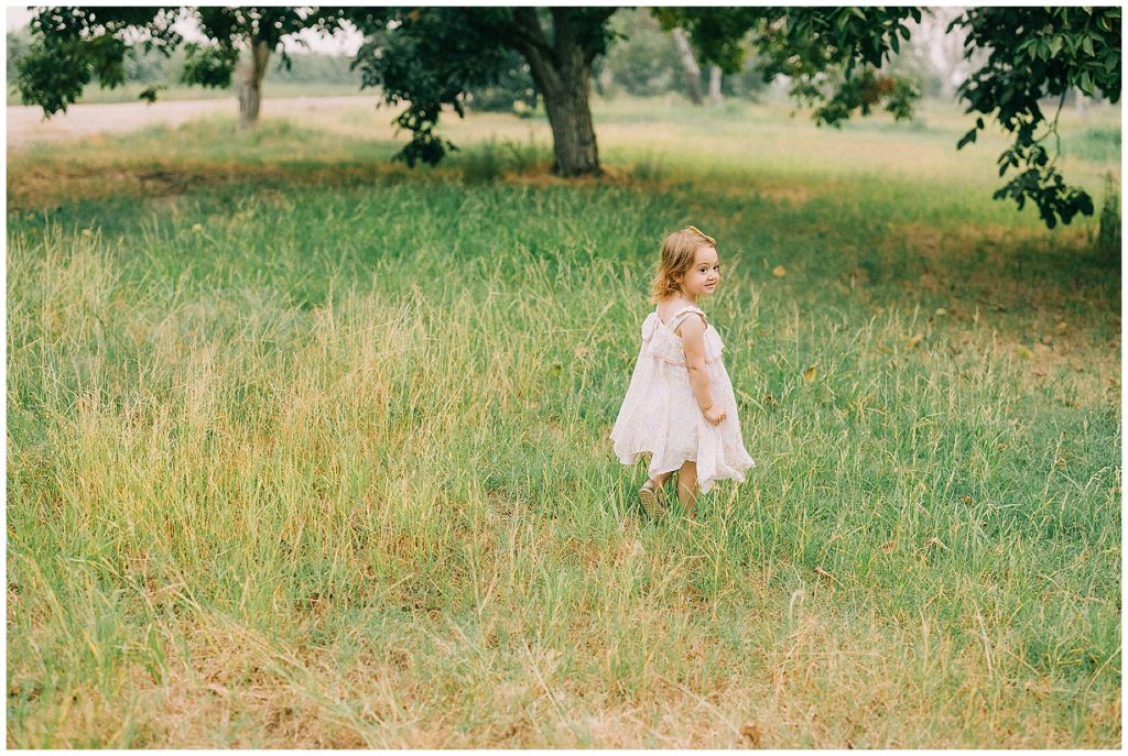 toddler girl running in grass field 