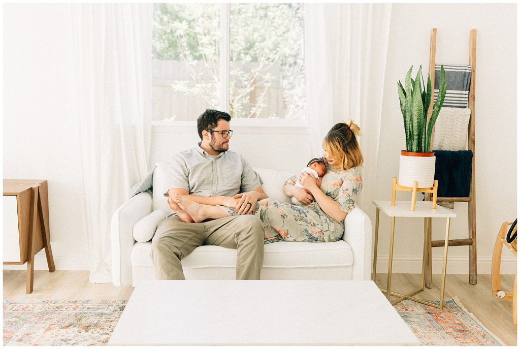 parents sitting on couch holding newborn