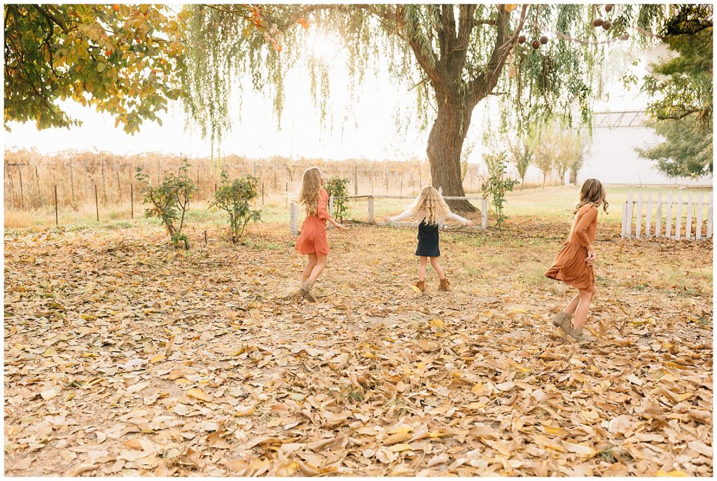girls playing together in fall leaves 