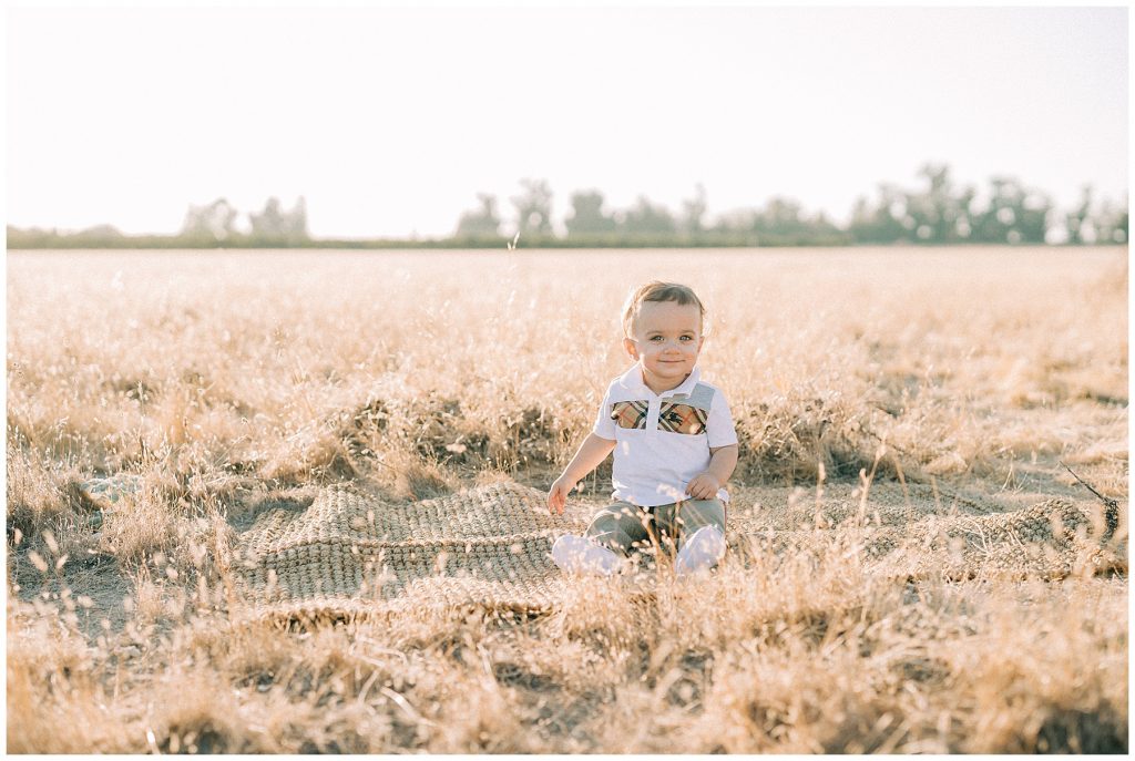 toddler boy sitting in field 
